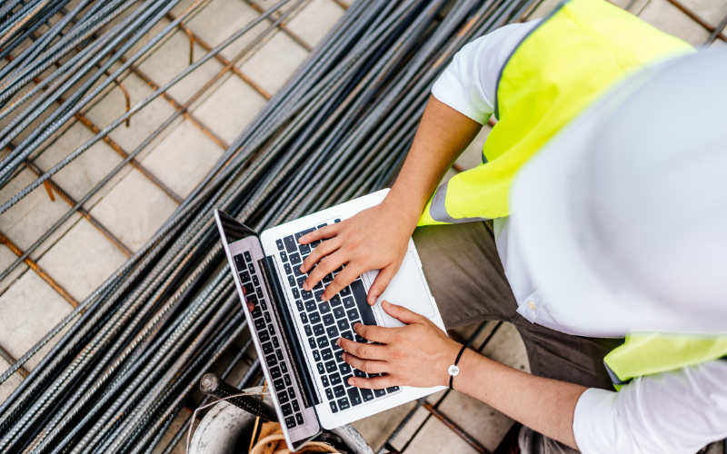 Construction worker typing on laptop.