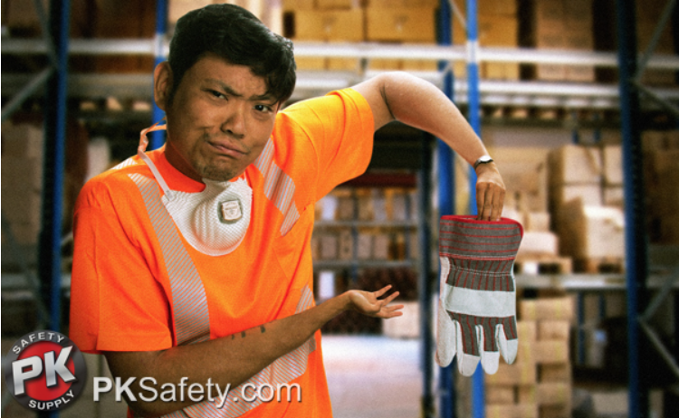 Warehouse worker holds up gloves. Wears respirator around his neck.
