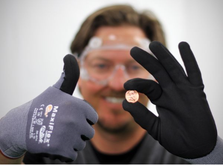 Man wearing safety glasses and gloves holds up a penny and give a thumbs up.