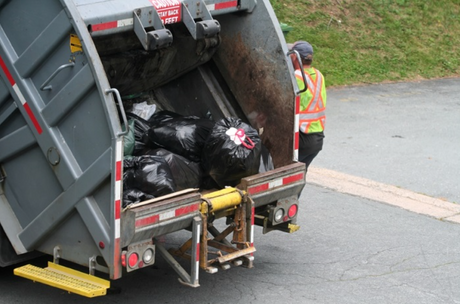 Garbage truck with plastic garbage bags and worker going to next stop.