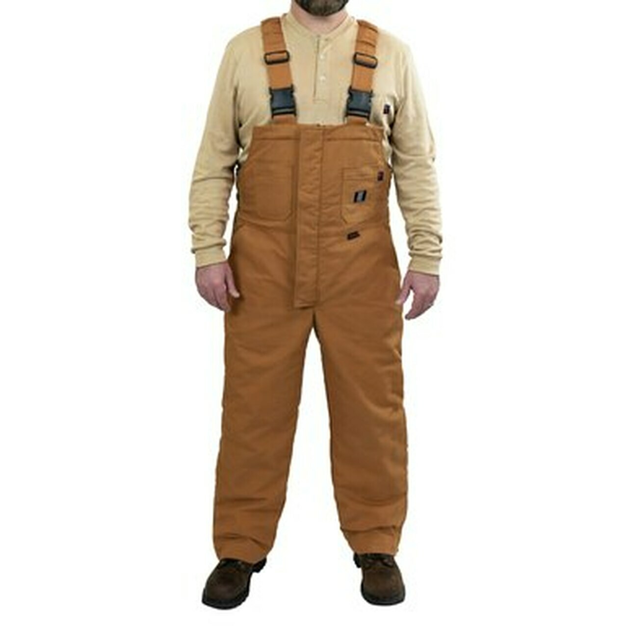 A person wearing tan insulated bib overalls and a beige long-sleeve shirt stands facing forward. The overalls feature front pockets and adjustable black straps. Brown shoes complete the outfit.