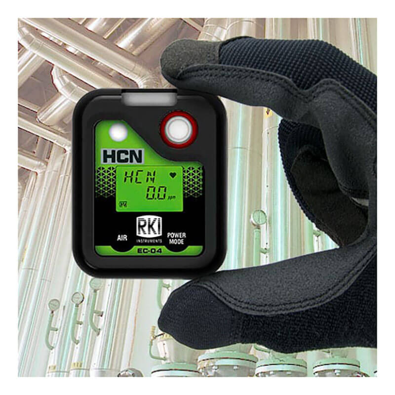A gloved hand holds an RKI Instruments SC-04 Series HCN Single Gas Monitor 73-0071, displaying 8.0 ppm, with industrial pipes and equipment in the background.