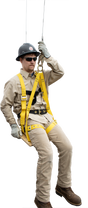 A person fully equipped with fall protection gear, including a helmet, gloves, and a high-visibility harness, demonstrates the French Creek Bosun Chair Work Seat 4754. They confidently sit on the platform outdoors with one leg bent, silhouetted by a fence and trees in the background.