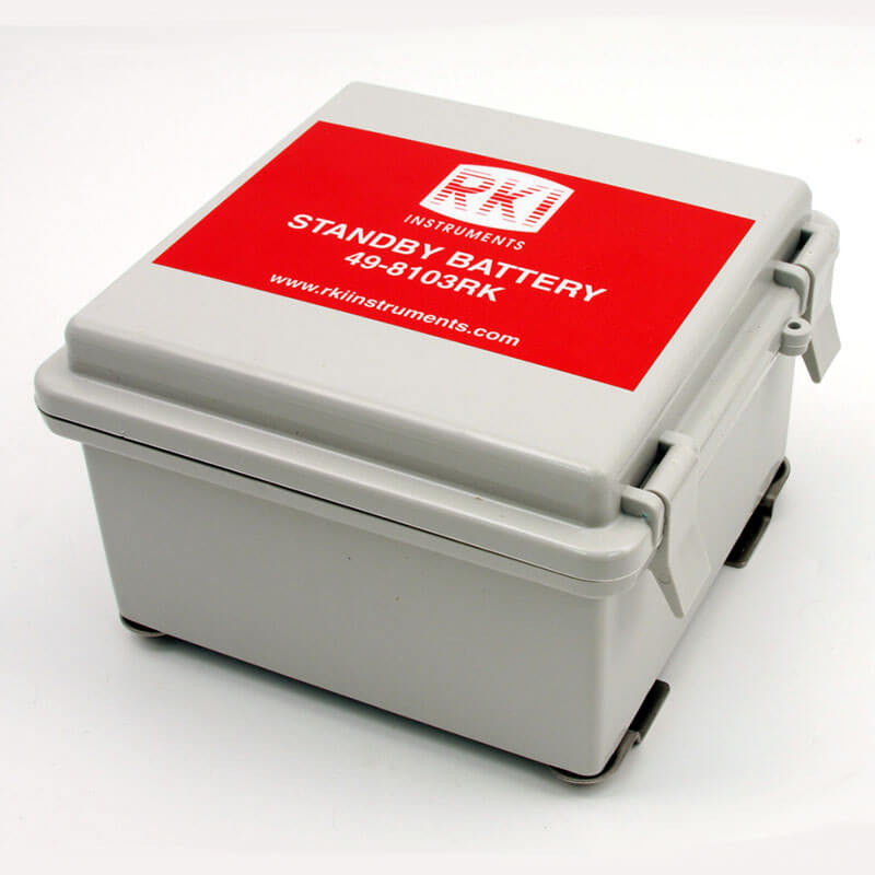 A gray RKI Standby Battery Assembly, model 49-8103RK by RKI Instruments, features a red label on the lid and secure side clasps. It provides 24 VDC power for Beacon compatibility and includes a website link to rkiinstruments.com.