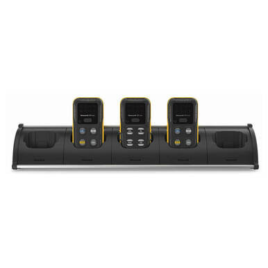 A black BW Honeywell 5 Way Cradle Charger for BW Icon/Flex CP-C01-5 is positioned at the center, accommodating three handheld devices. These gas detectors feature a yellow trim and multiple buttons and screens on their front panels, providing dependable gas detection in any environment.