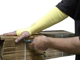 A person equipped with an MCR Safety Memphis 9378T Kevlar Knit Sleeve from a pack of ten is expertly cutting bundled cardboard sheets using a utility knife. The cardboard, held together by white bands, is managed with precision as the individual, dressed in dark clothing, depends on their Kevlar arm protector for safety.