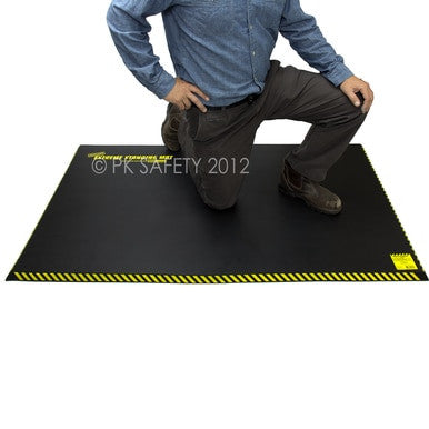 A person in a blue shirt and gray pants kneels on a Working Concepts ErgoKneel Extreme Standing Mat 5035, featuring yellow caution stripes and ensuring both safety and comfort during prolonged tasks.