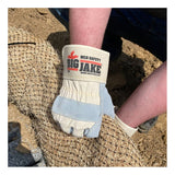 A person wearing MCR Safety Memphis Big Jake Premium Leather Palm Work Gloves grips a roll of net-like material outdoors on dirt, with only the gloved hands, part of their arm, and knee visible.