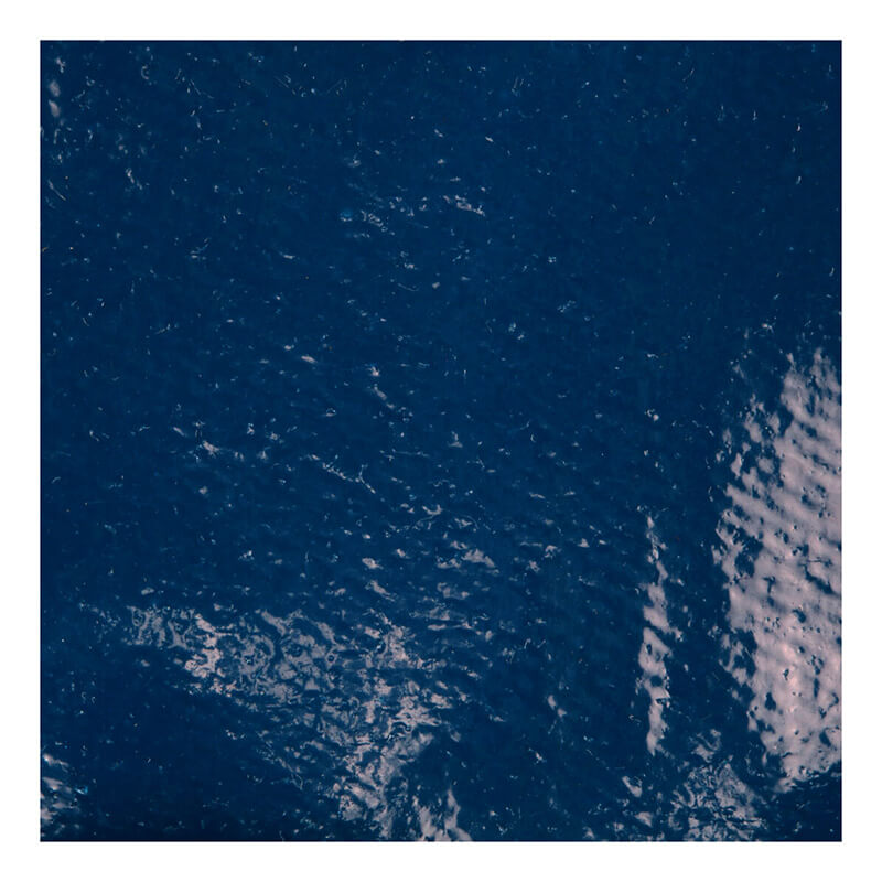 Close-up of the textured dark blue surface of an MCR Memphis Predator Nitrile Glove 9760 by MCR Safety, showing glossy reflections and uneven patterns, bordered by a white frame.