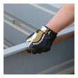 A person wearing MCR Safety Predator Leather Padded Multi-Task Gloves PD2903 grips a metal railing in an industrial setting, demonstrating the glove's superior grip and protection.