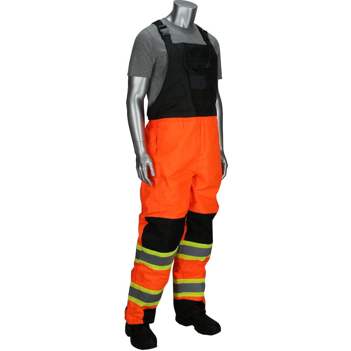 A mannequin showcases safety apparel, dressed in PIP Ripstop Insulated Two Tone Bib Overalls 318-1780 by Protective Industrial Products, featuring bright orange Class 3 overalls with reflective strips on the legs. The ensemble includes a black bib and straps, a gray shirt, and black shoes. The ripstop insulated fabric ensures enhanced durability for tough environments.