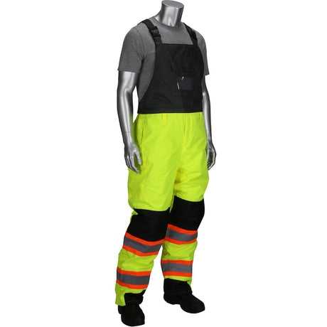 A mannequin features the PIP Ripstop Insulated Two Tone Bib Overalls 318-1780, designed by PIP - Protective Industrial Products. These Hi-Vis Yellow overalls highlight black accents and reflective orange stripes, meeting Class 3 apparel standards. Complemented by a gray short-sleeve shirt and black boots, the ensemble is set against a white background.