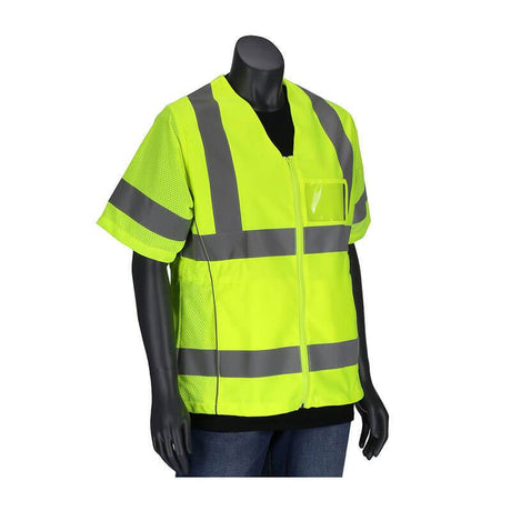 A black mannequin displays the PIP ANSI Type R Class 3 Women's Contoured Vest 303-0313 in bright yellow with gray reflective stripes, highlighting its high visibility design. This safety vest by PIP - Protective Industrial Products features short sleeves, a zippered front, and a transparent chest pocket, paired with a black shirt and blue jeans.