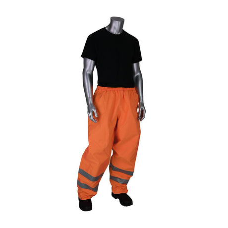 A mannequin is dressed in a black short-sleeve shirt, orange PIP VizPLUS Waterproof Breathable Pants 353-2002 featuring reflective stripes, and black shoes. The neutral pose highlights workwear attire certified as ANSI Class E hi-visibility apparel by PIP - Protective Industrial Products.