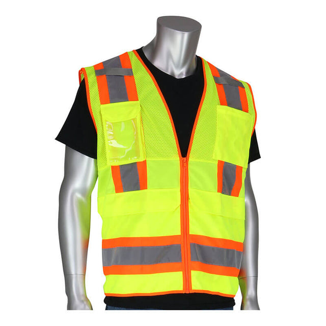 A mannequin is showcasing the PIP Yellow Class 2 Two-Tone Pocket Vest 302-0700-LY, which features fluorescent yellow with reflective orange and gray stripes over a black shirt. This PIP vest complies with ANSI/ISEA 107 Class 2 standards and includes pockets and a zipper front, providing both functionality and safety.