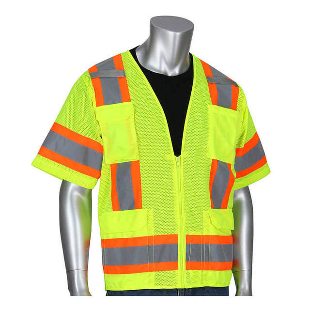 A silver mannequin showcases the PIP Lime Yellow Two Tone Surveyor 11 Pocket Vest Class 3 in bright lime yellow with orange and reflective gray stripes, worn over a black shirt. This ANSI Class 3 vest features two large pockets on the front. The mannequin stands against a plain white background, emphasizing the vest's striking design.