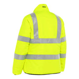 The PIP Bisley ANSI Type R Class 3 Women's Reversible Puffer Jacket is a high-visibility neon yellow piece with reflective silver stripes across the back and sleeves. It meets strict safety standards and features a raised collar for enhanced visibility. The "Bisley" label on the back of the collar signifies quality and reliability, merging safety with style from Protective Industrial Products.