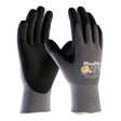 Two black and gray PIP MaxiFlex Endurance Micro-Foam Grip Glove 34-844 gloves are displayed upright, front and back visible. They feature a snug fit, textured nitrile-coated palms, and branding on the back.