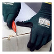 A person wearing PIP ATG MaxiFlex Cut Resistant Glove 34-8743 uses a red utility knife to cut open a sealed cardboard box along the tape.