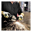 A person wearing SHOWA 4561 Cut Resistant Gloves by Showa Best operates an angle grinder, producing bright sparks. They are dressed in a black shirt against the backdrop of an industrial workspace.
