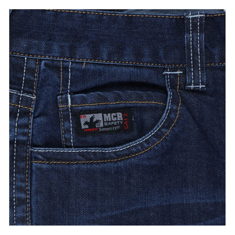 Close-up of MCR Safety FR Gear 10.5 oz Vintage Denim Jeans P2D, focusing on the front pocket with a black "MCR SAFETY" label and white stitching, highlighting durable flame resistant CAT2 protection.