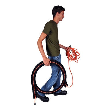 A person in a green shirt and blue jeans walks carefully, carrying a coiled black hose in one hand and an unwound orange cable in the other, mindful of avoiding tripping hazards. The plain white background underscores the importance of using the UltraTech Black Sidewinder System with Endcaps 1802 from UltraTech International for a dependable cable protection solution.