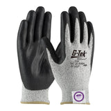 A pair of PIP G-Tek ECO Dyneema Phoenix gloves by Protective Industrial Products, featuring nitrile coated grips with black palms and gray fabric on the back. These gloves are designed for cut resistance and have safety certifications, while one glove is marked with a purple quality control sticker.