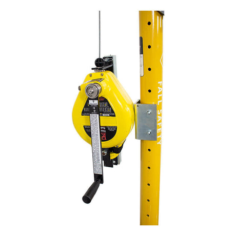 A French Creek Production's yellow 50ft Galvanized Rescue SRL R50G, equipped with a crank handle, is mounted on a pole labeled "FALL SAFETY." This device has a cable extending from the top, likely designed for safety or rescue operations.