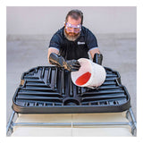 Donning safety goggles and gloves, a person uses the UltraTech IBC Funnel 0648 by UltraTech International to carefully transfer red liquid from a white bucket into a large black container. The container is securely positioned on a metal frame, highlighting the industrial setting's commitment to precision and chemical resistance.