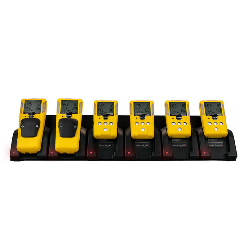 Six yellow WatchGas handheld gas detectors are charging in a black WatchGas SST 6 Way Bench Top Charger (model SST-6WSCC-KIT). Each detector features a display screen and buttons, and all are neatly aligned in a row, demonstrating an efficient six-device charging and centralized charging solution by WatchGas.