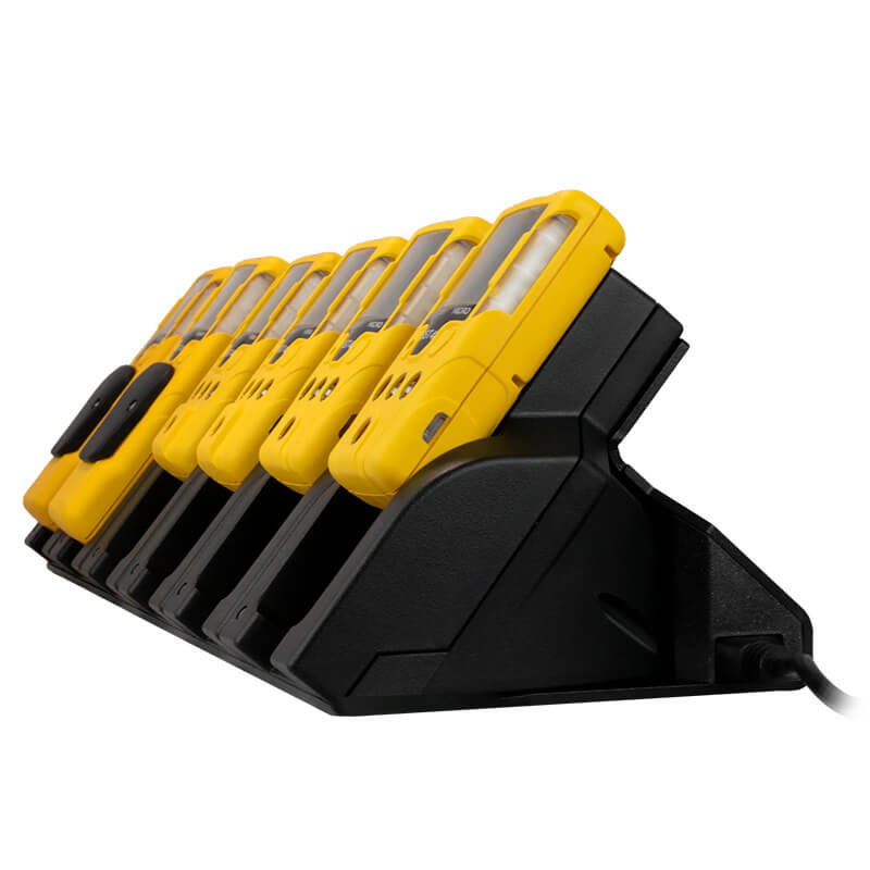 Six yellow handheld WatchGas devices are neatly arranged in a WatchGas SST 6 Way Bench Top Charger (SST-6WSCC-KIT), viewed from the side. This centralized solution from WatchGas efficiently charges up to six devices simultaneously, each uniform in shape and design.