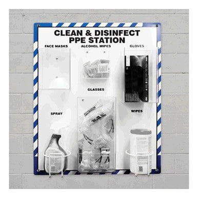 The AccuformNMC Clean & Disinfect PPE Station PRF300 is installed on a gray brick wall, underscoring workplace hygiene with clearly labeled compartments for face masks, alcohol wipes, gloves, spray, glasses, and wipes. Each section is neatly stocked with the appropriate personal protective equipment items.