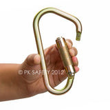 A person is holding a Skylotec Sidewinder TW Carabiner H-150, which is a large, gold-colored safety carabiner featuring a twist-lock gate for enhanced fall protection. The image displays the text "© PK SAFETY 2012" printed over it.