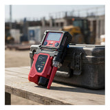 An RKI Instruments RP-3R Sample Drawing Pump for GX-3R rests on a gray hard case outdoors at a construction site, with blurred machinery and buildings visible in the background.