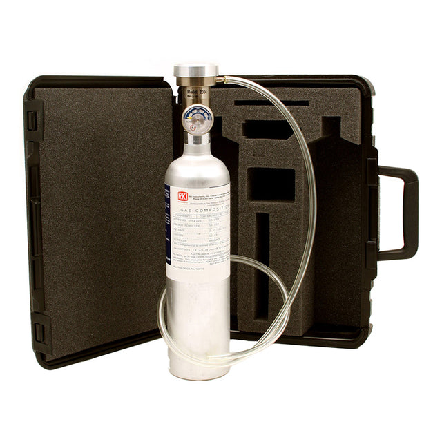 Displayed in front of an open black carrying case with custom foam padding, tailor-made for the RKI GX-2012 Calibration Kit by PK Safety Supply, is a silver gas cylinder featuring a pressure gauge and attached tubing. The case includes a handle on the right side to facilitate easy transport.