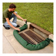A person kneels on a sidewalk, placing an UltraTech Filter Socks 945_ by UltraTech around a storm drain beside a grassy area to provide effective storm drain protection.