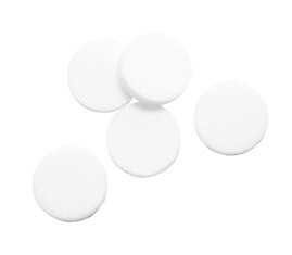 Five round white tablets are scattered against a plain background, reminiscent of the precision found in a Honeywell BW Particulate Pump Filter Replacement (5/Pack).