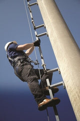 A worker, equipped with a safety harness and helmet, climbs a metal ladder attached to a tall pole under a clear blue sky, utilizing the 3M DBI-SALA Fall Protection DBI-SALA Lad-Saf X2 Detachable Cable Sleeve 6160030 for optimal ladder safety.