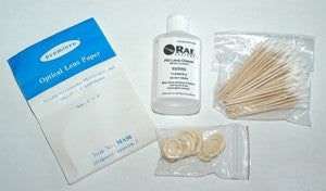 Introducing the RAE Systems Lamp Cleaning Kit w/ Methanol 081-0002-000, elegantly displayed on a white surface and including a bottle of precision cleaner, optical lens papers in a blue packet, cotton swabs, and three small plastic caps in a clear bag. This kit is perfect for maintaining photoionization detectors and ensuring precise gas detection.