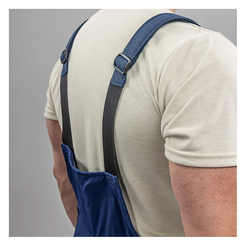 A person in a beige t-shirt wears NSA's Enespro ArcGuard Performance 40 Cal Arc Flash Bib ARC40B, featuring dark adjustable shoulder straps, shown from the back against a plain gray background—designed for arc flash protection.