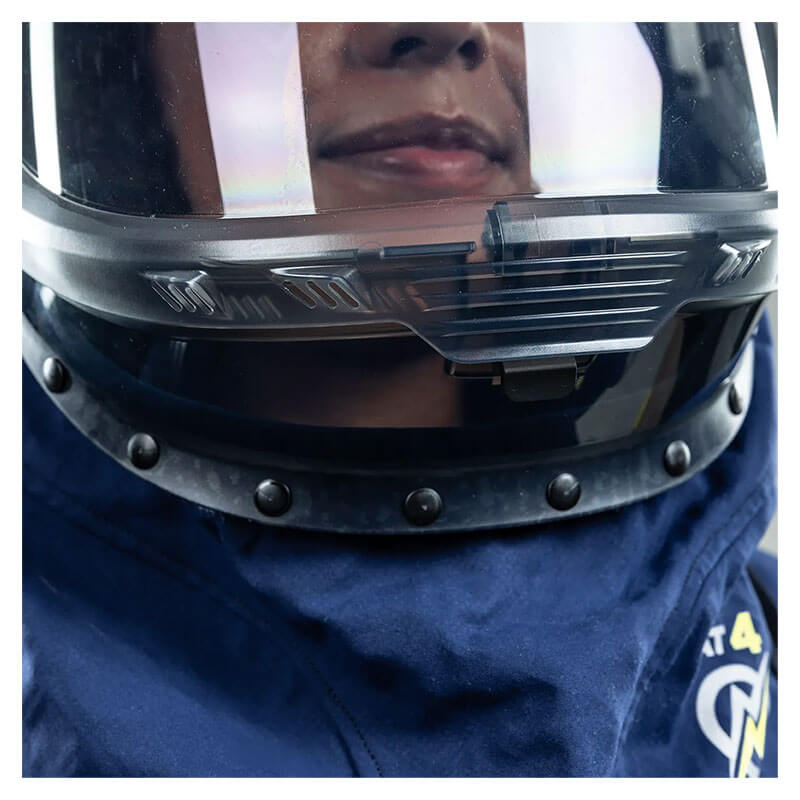Close-up of a person wearing the NSA Enespro ArcGuard Performance 40 Cal Lift Front Hood ARC40H, featuring a dark helmet, clear visor, and blue padded arc flash clothing with buttons and a hint of yellow emblem.