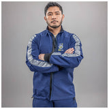 A man with short dark hair and a beard stands with arms crossed, wearing a blue NSA Enespro ArcGuard Performance 40 Cal Arc Flash Jacket (ARC40J) with silver reflective stripes and a "CAT 4 40 CAL" logo, against a plain gray background.