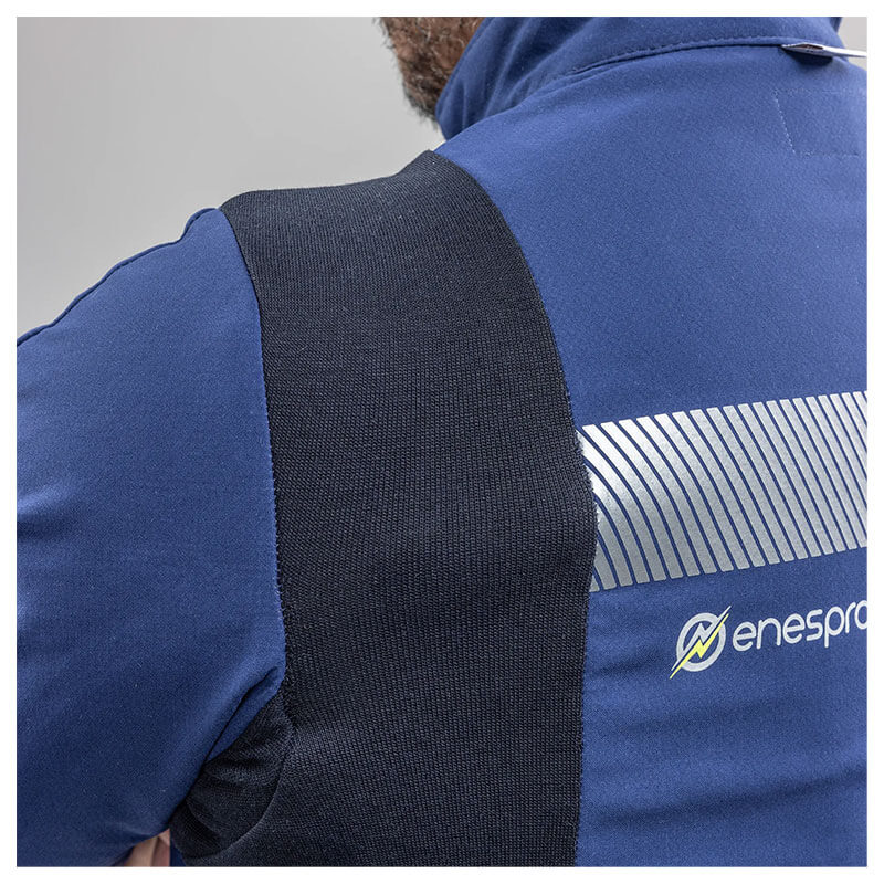 Close-up of a person wearing the blue and black NSA Enespro ArcGuard Performance 40 Cal Arc Flash Jacket (ARC40J) with reflective stripes and "enespro" logo, standing out against a plain, light background.