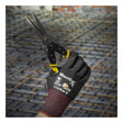 A gloved hand wearing PIP MaxiCut Ultra Nitrile MicroFoam A6 Gloves 44-6745F holds metal snips at a construction site, with steel reinforcing bars visible in the background.