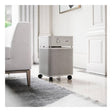 The Austin Air Systems HealthMate Machine B400, featuring medical grade HEPA filtration and convenient wheels, sits on a white floor next to a light gray rug and an upholstered chair in a bright, elegant living room, effectively capturing airborne viruses for cleaner air.