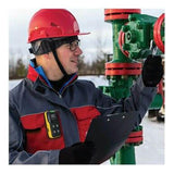 Wearing a red safety helmet and a blue and red work jacket, an individual holds a clipboard while inspecting a green industrial valve outdoors on a snowy day. To ensure safety, they are equipped with BW Honeywell's Honeywell BW Flex4 4-Gas Detector, protective glasses, and have a communication device attached to their jacket.