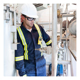 A worker in a navy blue coverall and safety gear inspects equipment, with a BW Technologies by Honeywell BW Clip4 4-Gas Detector BWC4-Y-N clipped to his chest pocket.