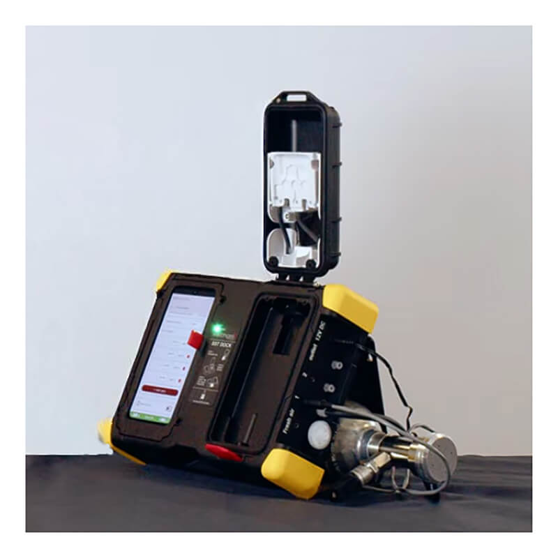 The WatchGas SST Dock Bundle by WatchGas, with yellow edges and a touchscreen, features metal connectors and an open lid revealing components for bump test or calibration gas on a dark surface.