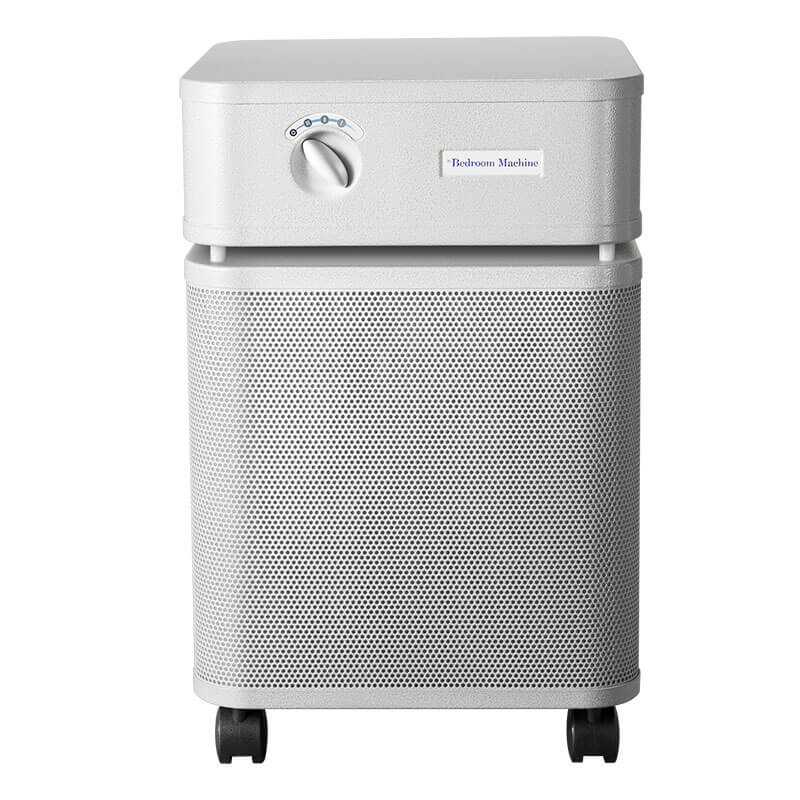 A white, rectangular air purifier with a vented front, control knob on top, and four black wheels. The label reads “Austin Air Bedroom Machine B402” by Austin Air Systems, featuring medical grade HEPA filtration for improved air quality.