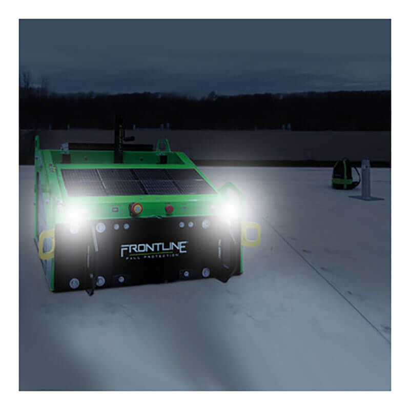 A green Commando Tank fitted with the Frontline Fall Protection "Frontline Solar Panel System for Commando Tank SLR-PAN" is outdoors on a flat surface at night, headlights on, with dark trees and a cloudy sky in the background.